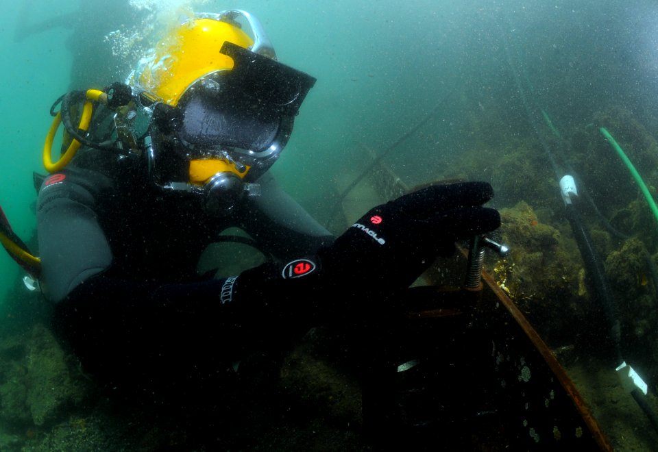 US Navy 110804-N-XD935-310 Navy Diver 3rd Class Bryan Myers uses a clamp to secure a steel plate before conducting welding operations