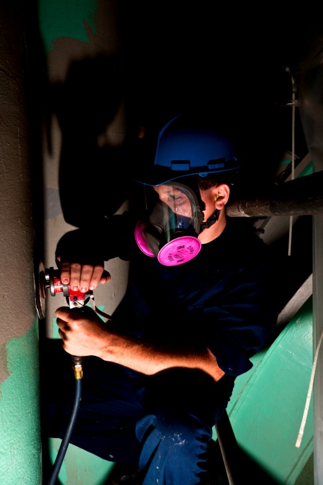 US Navy 110810-N-FG395-038 oatswain's Mate 1st Class Johnathon C. Plemons uses a power grinder inside the superstructure of USS Florida (SSGN 728)