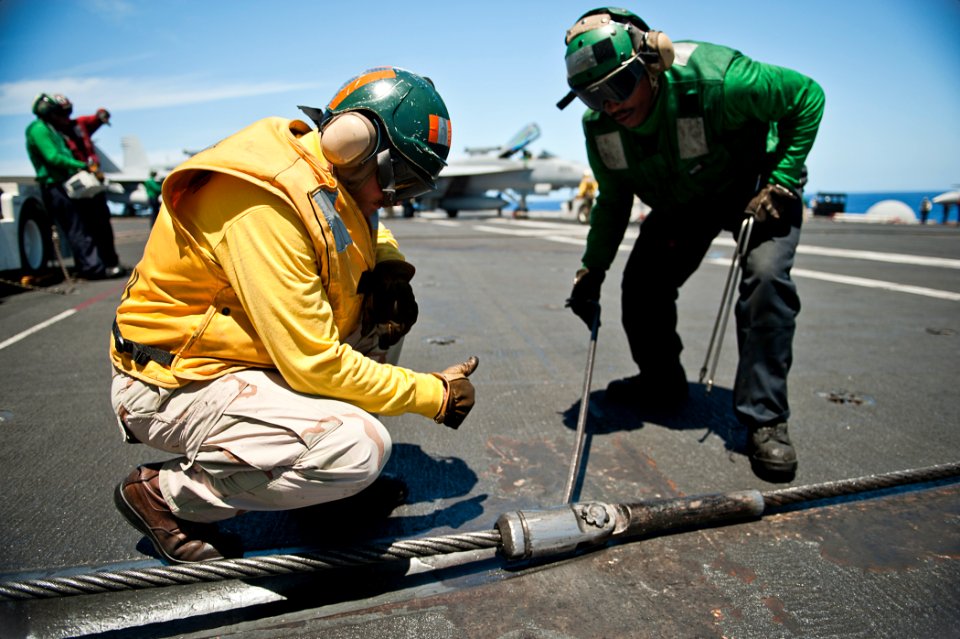 US Navy 110810-N-BT887-142 Lt. Stephen Hiers and Aviation Boatswain's Mate (Equipment) Airman Lional Alexander inspect an arresting gear cable aboa