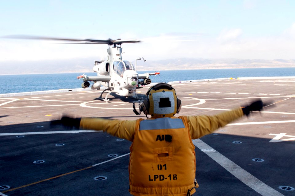 US Navy 110810-N-PB383-355 Aviation Boatswain's Mate (Handling) 2nd Class Kelley Soucy guides a Marine Corps AH-1Z Viper attack helicopter