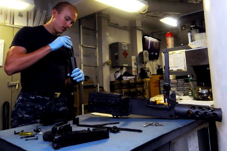 US Navy 110810-N-JD217-016 Aviation Ordnanceman Airman Matthew R. Howe performs maintenance on a .50-caliber machine gun in the armory aboard the a