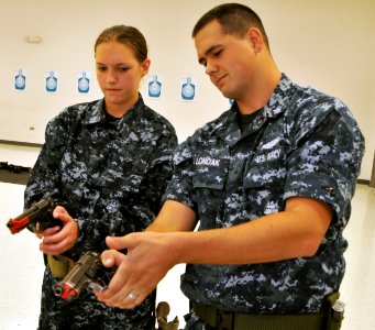 US Navy 110811-N-IK959-991 A Sailor teaches a midshipman how to probably handle a 9mm Beretta pistol