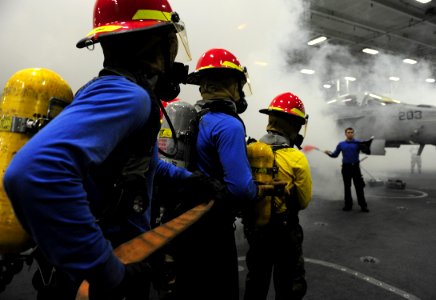 US Navy 110813-N-ED900-466 ose team members battle a simulated aircraft fire in hangar bay one during a general quarters drill aboard the USS John