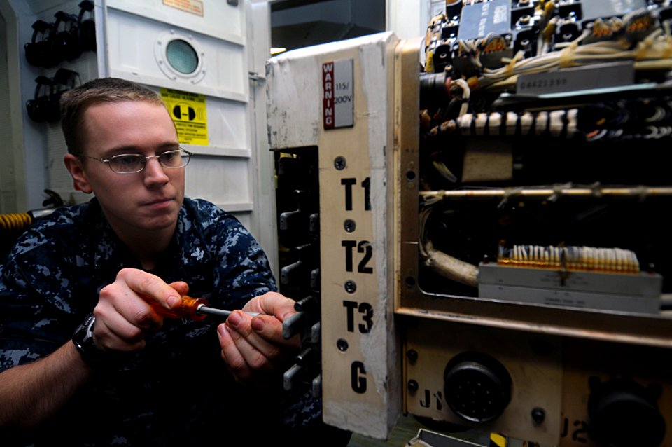 US Navy 110814-N-JD217-016 Aviation Electrician's Mate 2nd Class Keith A. Benjamin repairs a motor generator aboard the aircraft carrier USS George