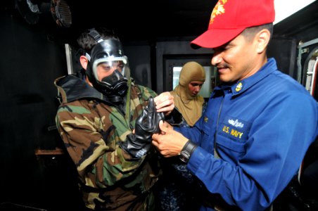US Navy 110817-N-KM175-002 Chief Damage Controlman Arturo Chavez helps Damage Controlman 3rd Class Daniel Obrien don chemical, biological and radio