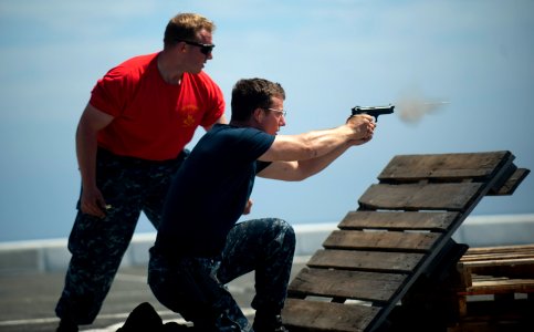 US Navy 110817-N-PB383-008 Seaman Keith Frisbie fires a 9mm pistol while Gunner's Mate 2nd Class Adrian Rodziewicz observes for safety during a sma