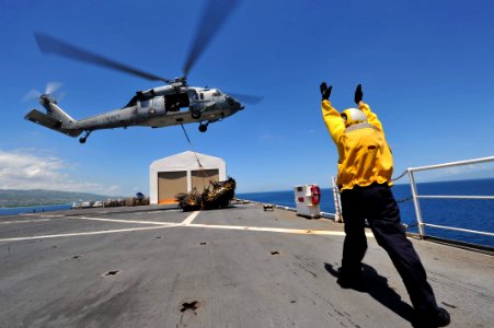 US Navy 110818-F-NJ219-064 A Sailor guides an MH-60S Sea Hawk helicopter toward a pallet of supplies