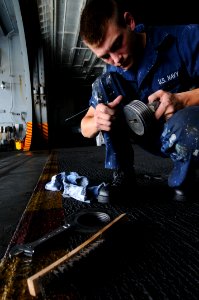 US Navy 110813-N-XE109-070 Seaman Tommy A. Ward performs maintenance on a Baxter bolt in the hangar bay aboard the aircraft carrier USS George H.W