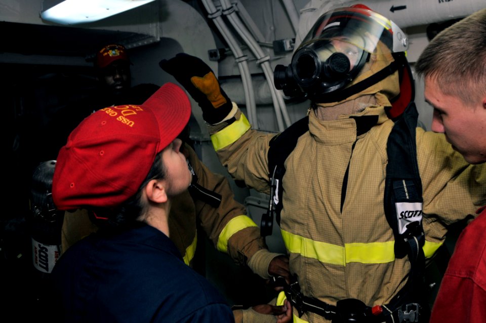 US Navy 110817-N-GW695-142 Damage Controlman 1st Class Angela Powell, left, inspects Damage Controlman Fireman Colin Mills during a damage control