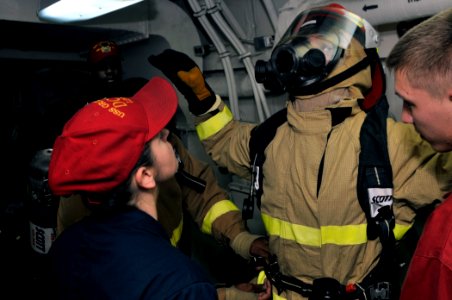 US Navy 110817-N-GW695-142 Damage Controlman 1st Class Angela Powell, left, inspects Damage Controlman Fireman Colin Mills during a damage control