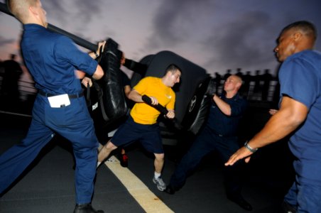 US Navy 110820-N-DU438-825 Culinary Specialist 3rd Class Eric Raffaniello, center, uses a baton to push back mock suspects after being sprayed with