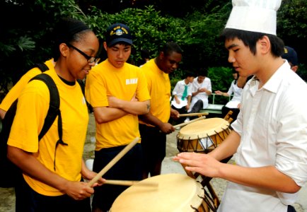 US Navy 110817-N-XG305-240 Seaman Daynesha Lewis, assigned to the U.S. 7th Fleet command ship USS Blue Ridge (LCC 19), receives a drumming lesson f