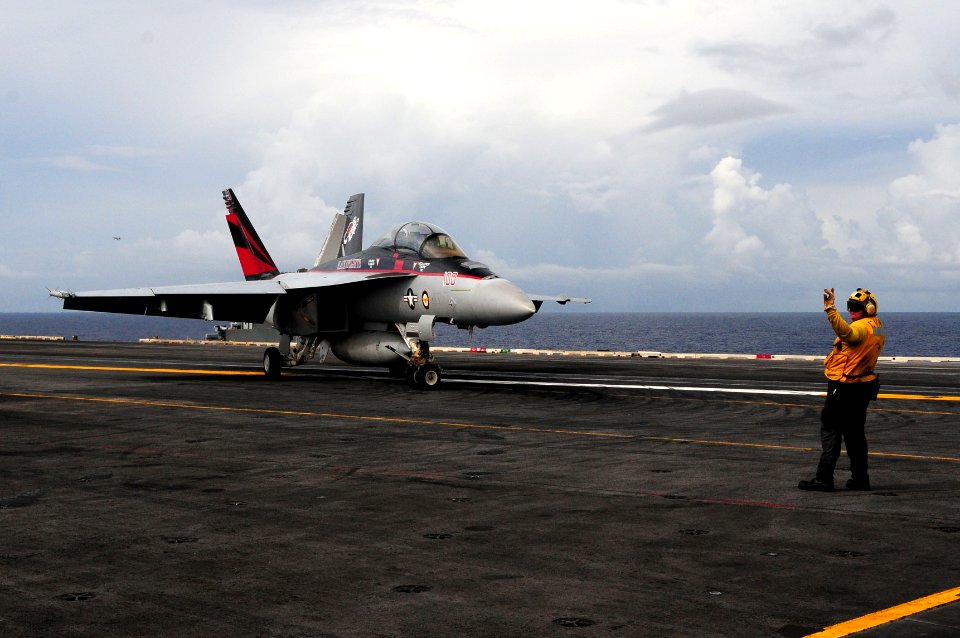 US Navy 110824-N-UO379-471 Aviation Boatswain's Mate (Handling) 1st Class Robin Calcaterra directs an F-A-18F Super Hornet assigned to the Black Kn