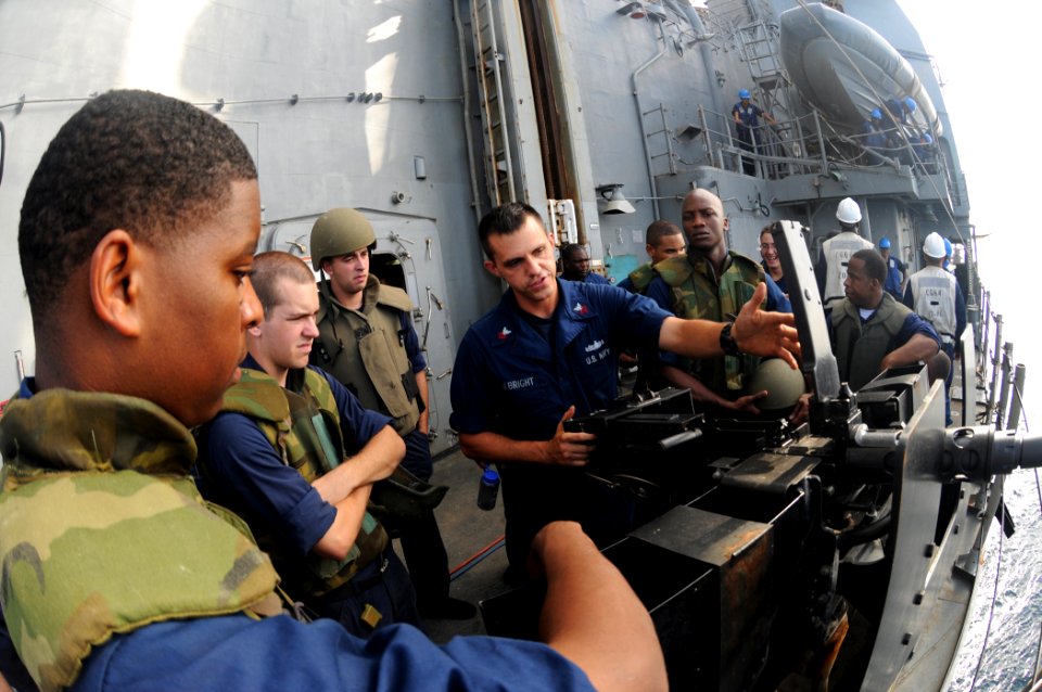 US Navy 110819-N-DU438-300 Gunner's Mate 1st Class Merle Albright, center, instructs Sailors how to properly handle a 50-caliber machine gun aboard