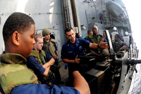 US Navy 110819-N-DU438-300 Gunner's Mate 1st Class Merle Albright, center, instructs Sailors how to properly handle a 50-caliber machine gun aboard