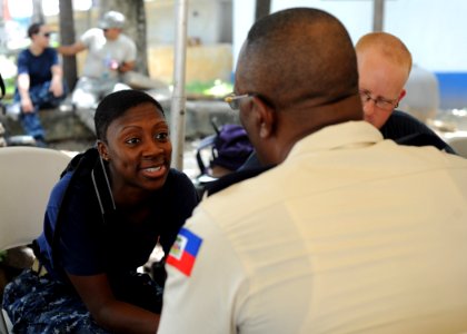 US Navy 110818-N-NY820-319 Lt. j.g. Djenane Jean-Baptiste, a Haitian-American, talks with a patient at the Killick Haitian Coast Guard Base surgica photo