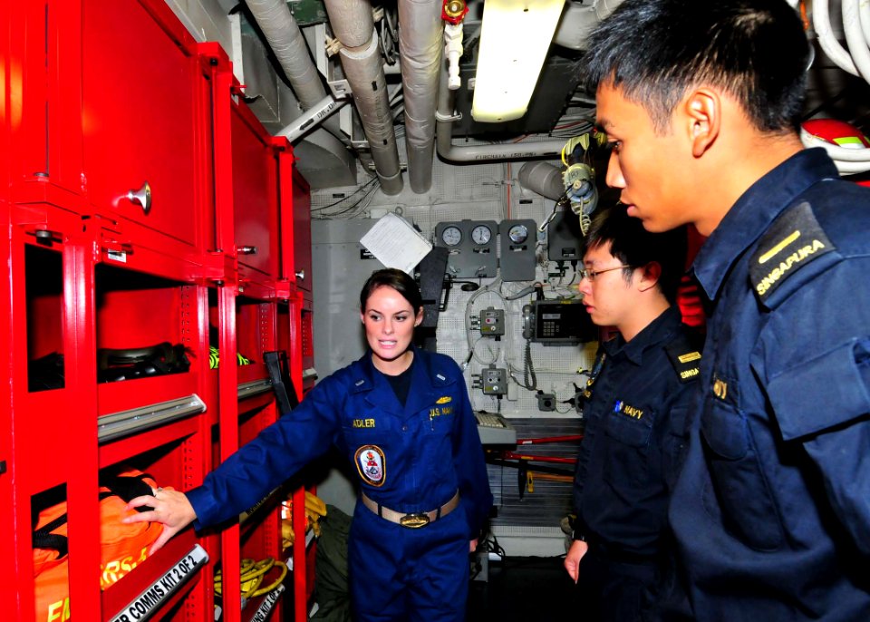 US Navy 110825-N-XR557-091 Damage Control Assistant Lt. j.g. Caroline Adler, left, shows Republic of Singapore navy officers Lt. Bryan Low, center