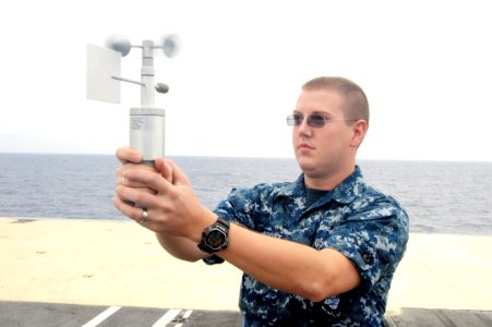 US Navy 110826-N-AU622-016 Aerographers Mate Airman John Abbott measures wind speed and direction with an anemometer on the bow of the aircraft car