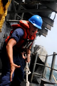 US Navy 110825-N-DU438-149 Cryptologic Technician (Collection) 2nd Class Matthew Langston heaves a line aboard the guided-missile cruiser USS Getty