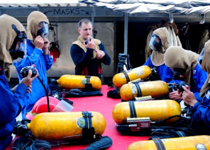 US Navy 110824-N-VY256-396 Damage Controlman 1st Class Joe Beier demonstrates how to use a self-contained breathing apparatus to sailors assigned t
