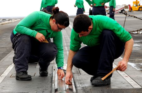 US Navy 110826-N-KF029-041 Aviation boatswain's mates clean a catapult on the flight deck aboard the aircraft carrier USS Ronald Reagan (CVN 76)
