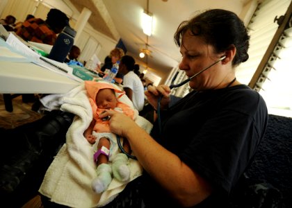 US Navy 110828-N-NY820-087 Cmdr. Laurie Hale examines an infant at a temporary medical site at the Killick Coast Guard Base during Continuing Promi photo