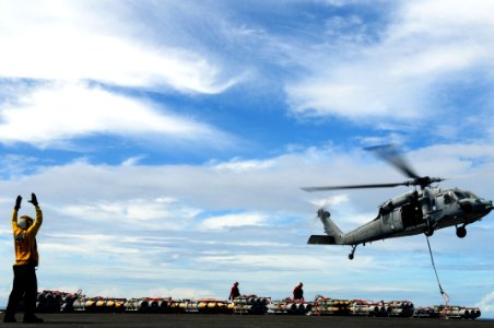US Navy 110828-N-SB672-308 Aviation Boatswain's Mate (Handling) 3rd Class Fabian Cervantes signals to an MH-60S Sea Hawk helicopter as it lifts a p