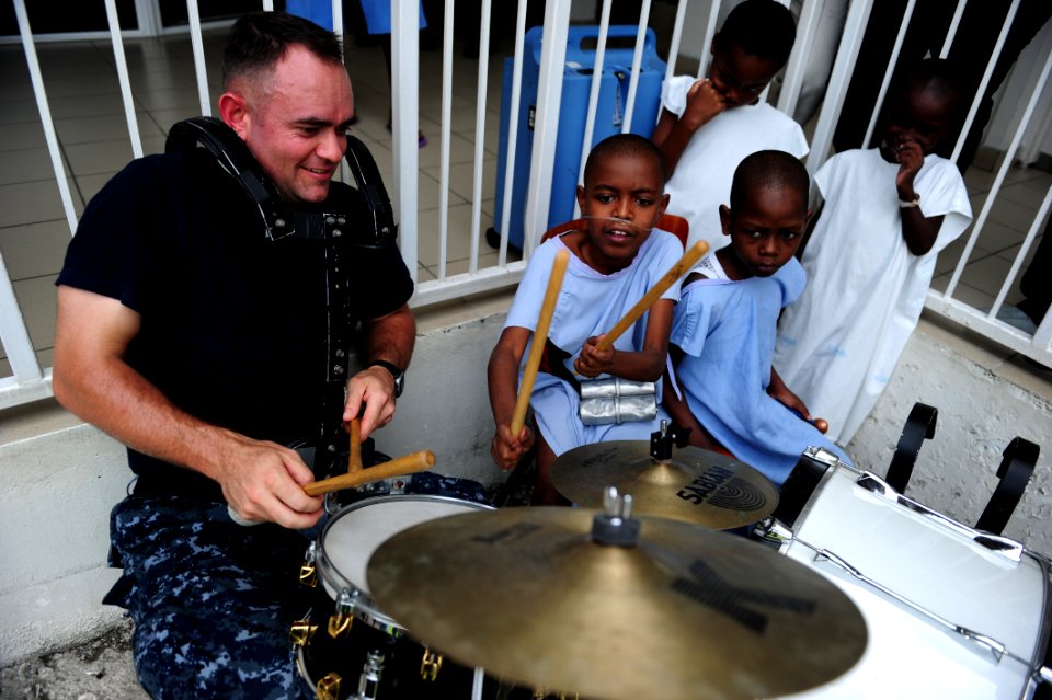 US Navy 110828-N-QD416-133 U.S. Fleet Forces Band member Musician 2nd Class David Ward plays the drums with a patient at St. Damien Hospital