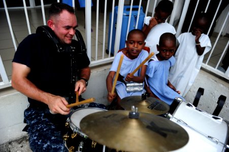 US Navy 110828-N-QD416-133 U.S. Fleet Forces Band member Musician 2nd Class David Ward plays the drums with a patient at St. Damien Hospital