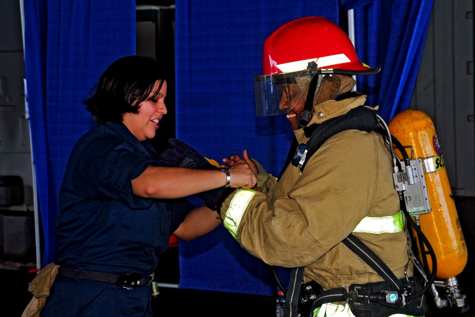 US Navy 110827-N-SF704-095 Damage Control Fireman Teresita Hernandez finishes dressing out a guest in a firefighting ensemble during a friends and