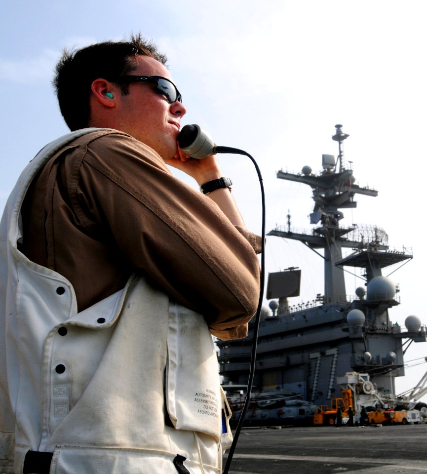 US Navy 110828-N-XE109-287 Lt. j.g. Jon Boyer guides an F-A-18E Super Hornet as it lands aboard USS George H.W. Bush (CVN 77)