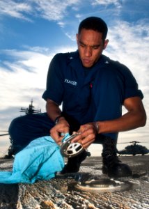 US Navy 110830-N-ZZ999-015 Electrician's Mate 3rd Class Egbert Alexander performs preventative maintenance on a spot pad on the flight deck of USS