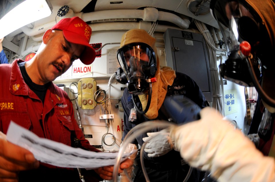 US Navy 110829-N-DU438-111 Chief Damage Controlman Timothy Spare, left, reads instructions to analyze the toxicity in the air during a toxic gas ex