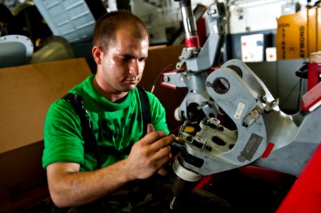 US Navy 110831-N-BT887-312 Aviation Machinist's Mate Airman Nicholas Simnick performs maintenance on the spindle of an MH-60R Sea Hawk helicopter