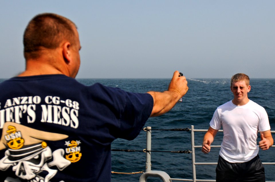 US Navy 110831-N-YM590-198 Chief Master-at-Arms Jeffrey Barnes sprays Operations Specialist Seaman Apprentice Brandon Cain with oleoresin capsicum
