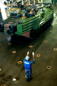 US Navy 110905-N-PB383-230 Seaman Earl Simon guides an amphibious assault vehicle (AAV) in the well deck of the amphibious transport dock ship USS