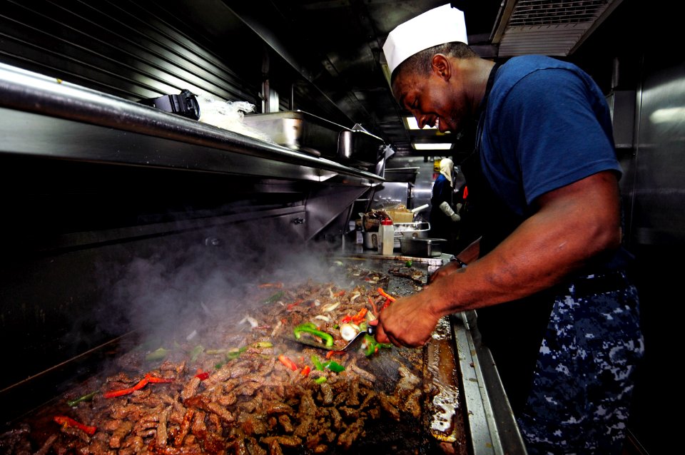 US Navy 110906-N-RC734-028 Culinary Specialist 2nd Class Sanford McCants prepares beef fajitas for the lunch meal aboard USS Comstock (LSD 45)