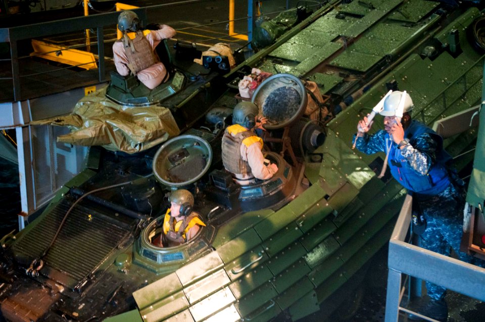 US Navy 110905-N-PB383-353 Seaman Jomel Bonner guides an amphibious assault vehicle (AAV) in the well deck of the amphibious transport dock ship US