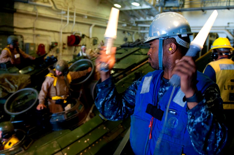 US Navy 110905-N-PB383-105 Seaman Jomel Bonner guides an amphibious assault vehicle (AAV) in the well deck of the amphibious transport dock ship US