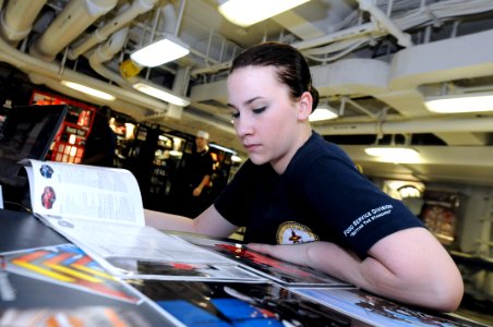 US Navy 110907-N-QL471-080 Aviation Electronics Technician Airman Sarah G. Cessor reads a new car brochure on the mess decks aboard the aircraft ca