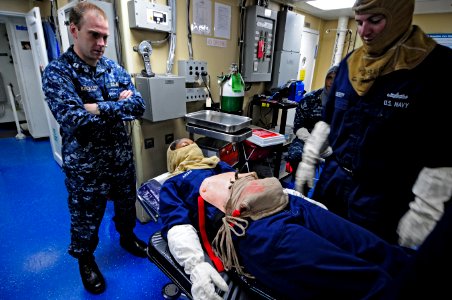 US Navy 110906-N-RC734-006 Lt. Ryan Buckley, left watches as Boatswain's Mate 2nd Class David Liberty, right, cares for a simulated medical casualt