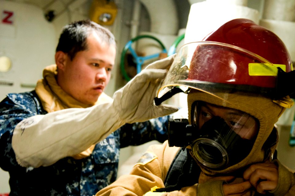 US Navy 110909-N-PB383-414 Ship's Serviceman Seaman Apprentice Kunlei Wu helps Ship's Serviceman 3rd Class Guangfeng Zhang put on firefighting equ