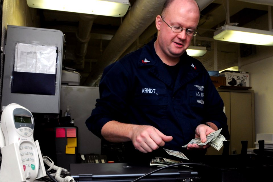 US Navy 110907-N-JD217-022 Personnel Specialist 2nd Class Frank J. Arndt counts money in the disbursing office aboard the aircraft carrier USS Geor