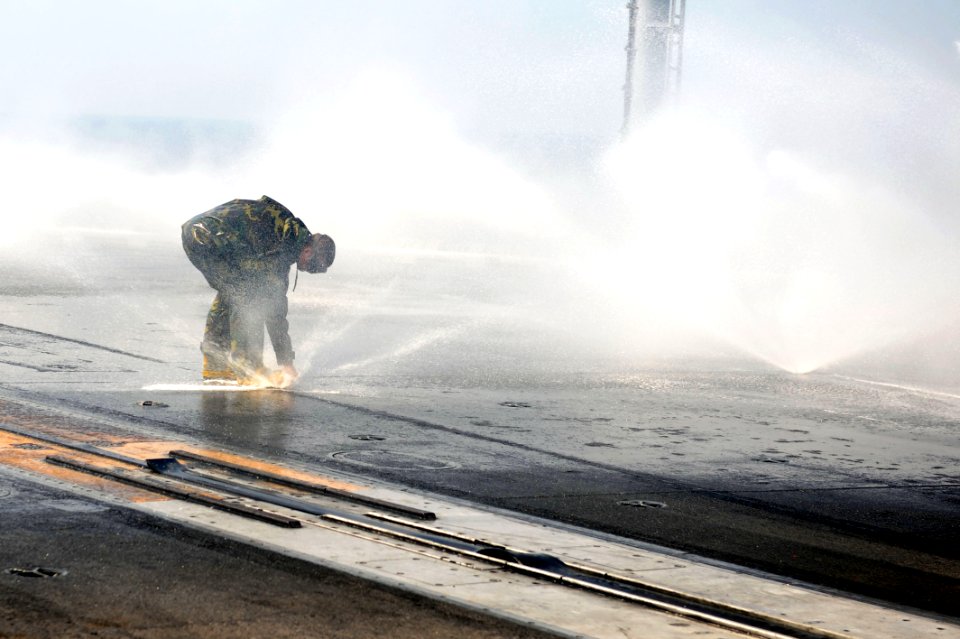 US Navy 110912-N-AU622-041 Aviation Boatswain's Mate (Handling) 3rd Class Zachary Stump inspects a sprinkler on the flight deck of the aircraft car