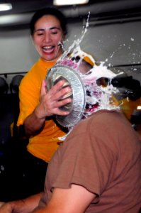 US Navy 110912-N-RC734-066 Ensign Patricia Cunanan shoves a pie in the face of Command Master Chief Michael Lucas during a fundraiser aboard the am