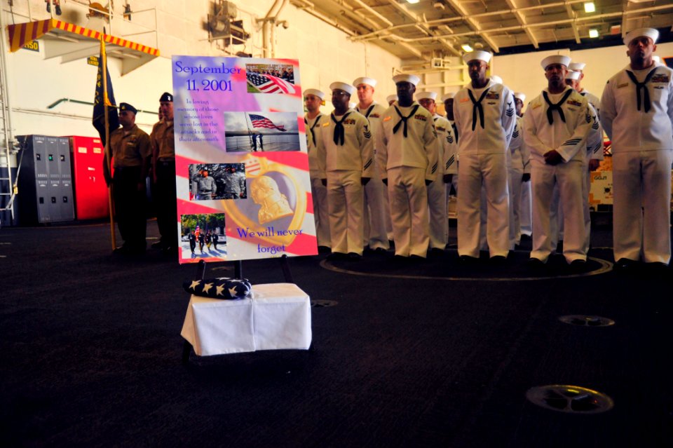 US Navy 110909-N-MH885-032 The national ensign lays at the foot of a poster commemorating lives lost during the Sept. 11, 2001, terrorist attacks d
