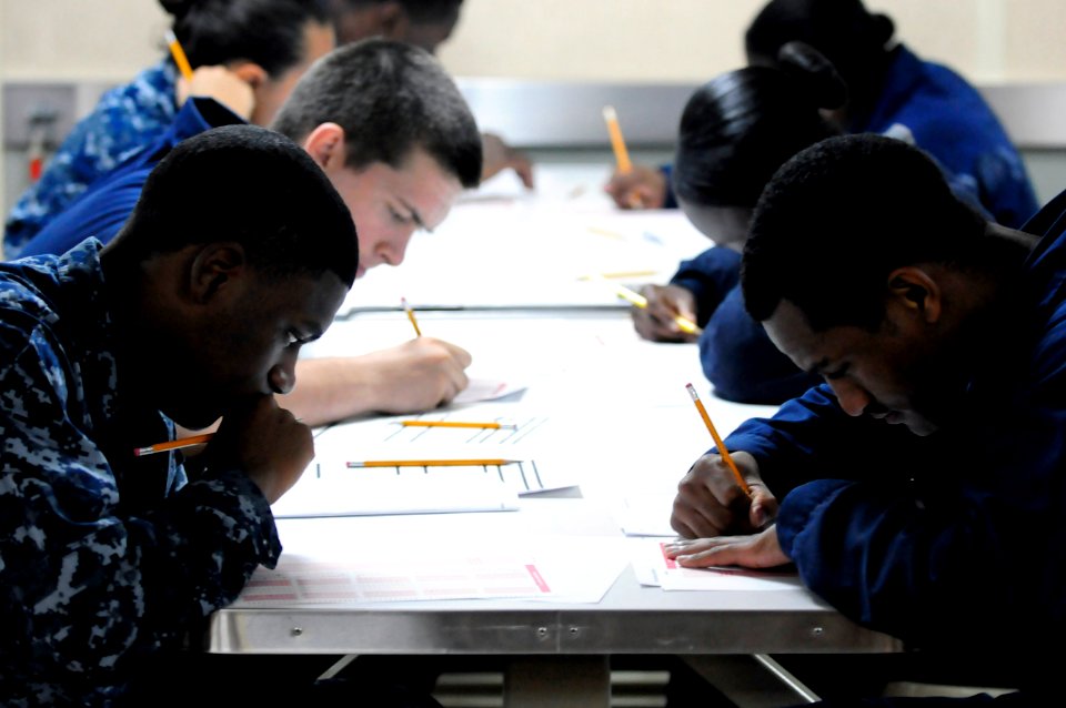 US Navy 110915-N-RC734-041 Sailors participate in the E-4 advancement examination on the mess decks aboard the amphibious dock landing ship USS Com