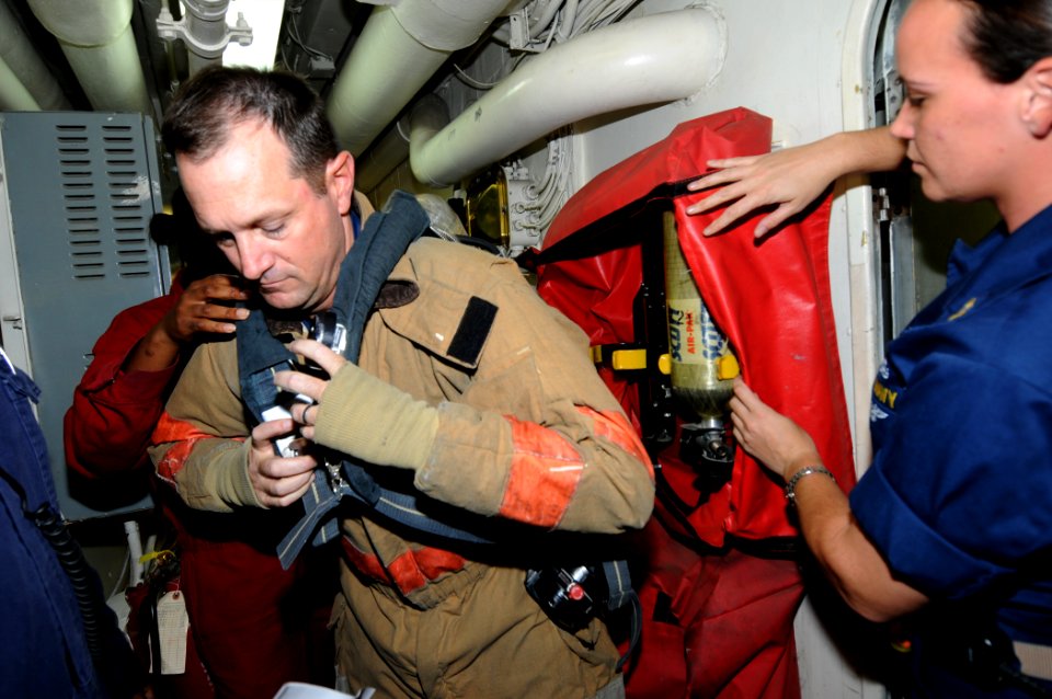 US Navy 110912-N-DU438-077 Command Master Chief Brent Tidwell dons a self-contained breathing apparatus during a drill aboard the guided-missile cr