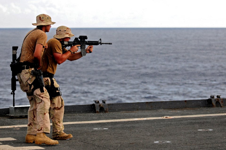 US Navy 110919-N-RC734-497 Gunner's Mate 2nd Class Kyle Galow demonstrates the course of fire during a small arms live-fire exercise aboard the amp