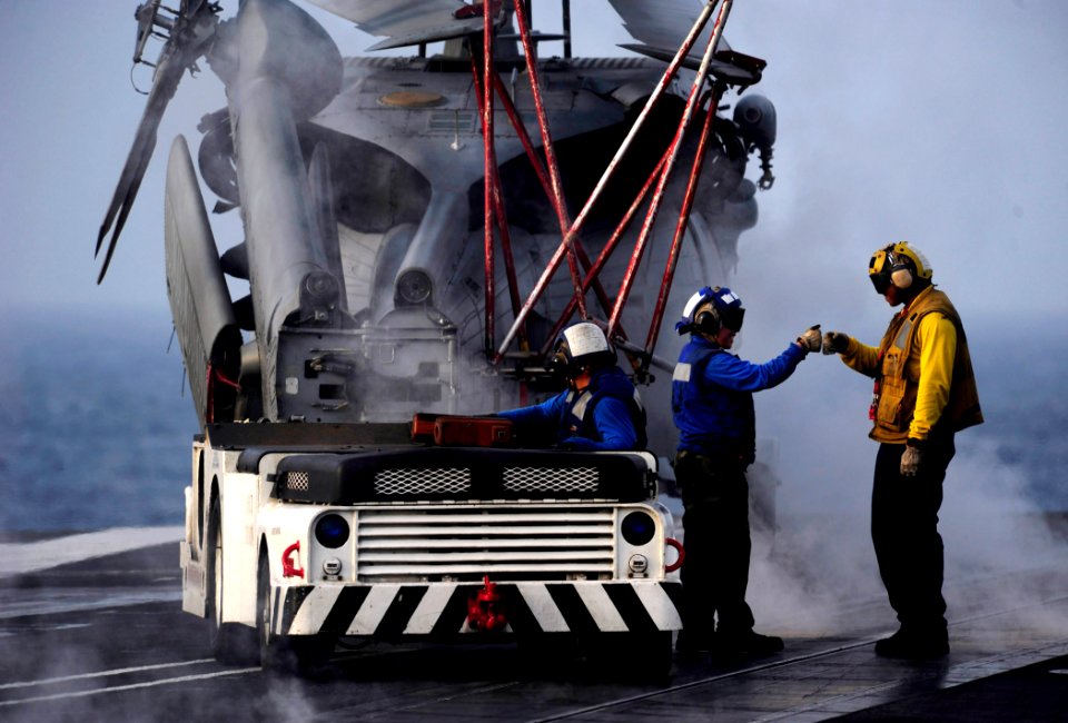 US Navy 110918-N-ZZ999-508 Aviation boatswain's mates prepare to move an MH-60S Sea Hawk helicopter assigned to the Eightballers of Helicopter Sea